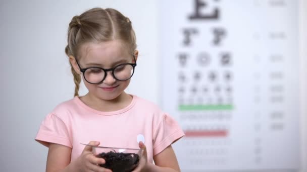 Улыбающаяся девушка в очках ест чернику, натуральные витамины для улучшения зрения — стоковое видео