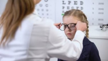 Gözlük takmayı reddeden kız öğrenci, gözlük çünki gözlük seçmeye yardım eden gözlükçü