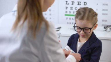 Optisyen küçük kıza hap veren, göz hastalığı tedavisi, görme vitaminleri