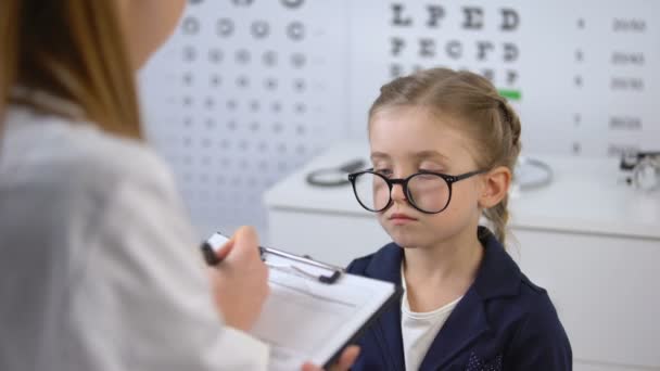 Оптометрист выписывает очки, чтобы расстроить ребенка, рекомендации по лечению глаз — стоковое видео