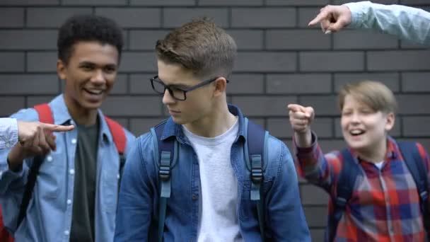 Wrede schoolkinderen wijzende vingers bij student, spottende slimme jongen, pesten — Stockvideo