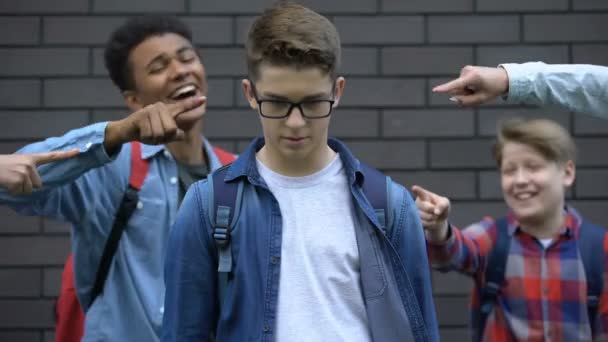 Мальчик смело смотрит в камеру, несмотря на насмешки над одноклассниками, сопротивляясь издевательствам — стоковое видео
