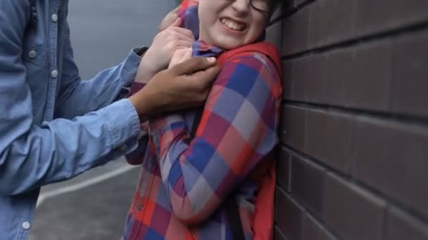 Cruel teenager pushing nerd boy to wall, threatening physical harm, bullying — Stock Video