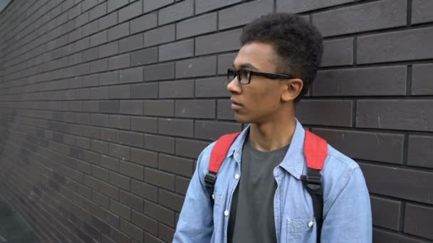 Impudent tiener het wegnemen van een bril van onveilige zwarte jongen, spottende slecht zicht — Stockvideo