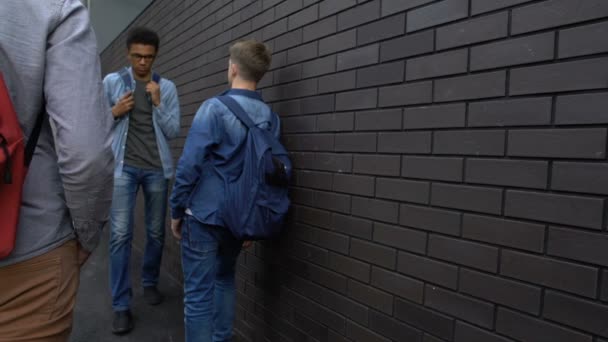 Estudiantes siguiendo a un chico con aspecto desagradable, desprecio civil, racismo en las escuelas — Vídeo de stock