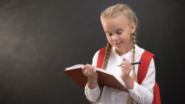 Rüya gibi küçük kız öğrenci not defterine yazıyor, tahtaya karşı ödev yapıyor