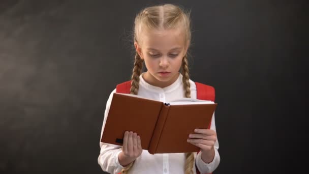 Έξυπνο θηλυκό παιδί διαβάζει το βιβλίο, μαυροπίνακα στο παρασκήνιο, δίψα για γνώση — Αρχείο Βίντεο