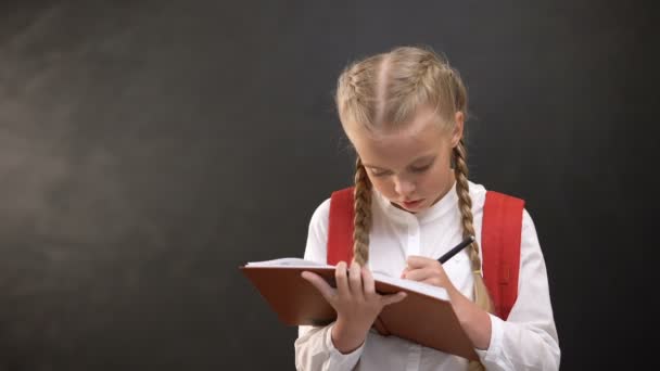 Удумлива дівчинка з рюкзаком робить домашнє завдання, маючи ідею, освіту — стокове відео