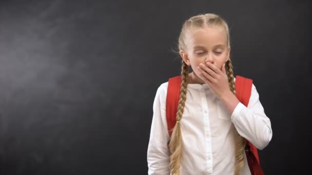 Sleepy schoolgirl yawning on camera against blackboard, tiredness after lessons — Stock Video