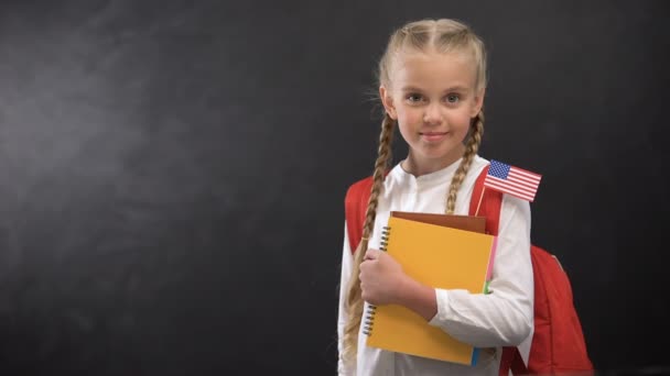 Симпатичні школярка тримає книги з крихітним прапором США готова вивчати іноземну мову — стокове відео