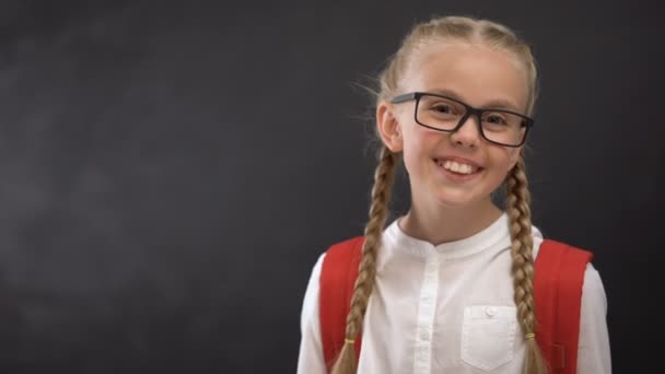 Умная школьница в очках, улыбающаяся на камеру, жаждущая знаний — стоковое видео