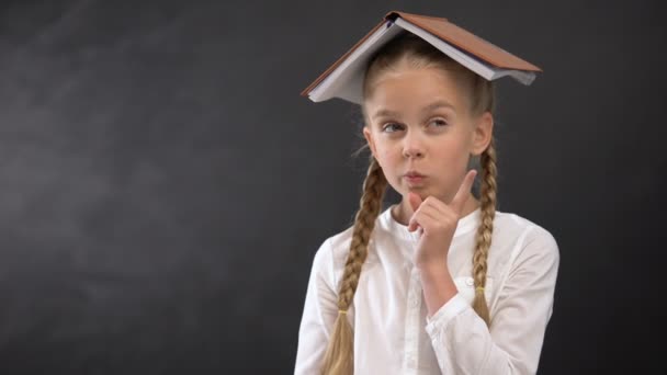 Engraçado colegial com livro na cabeça planejamento de casa agenda, conceito de educação — Vídeo de Stock