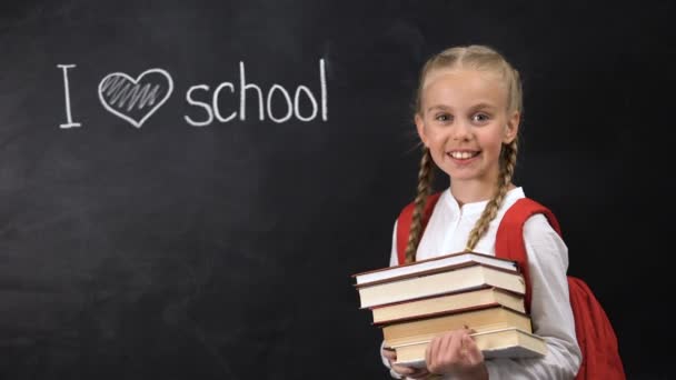 Lächelndes Schulmädchen mit Büchern, ich liebe Schule, die auf Tafel geschrieben ist, Unterricht — Stockvideo