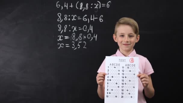 Ijverige lachende school jongen met uitstekende test, wiskunde oefening geschreven achter — Stockvideo