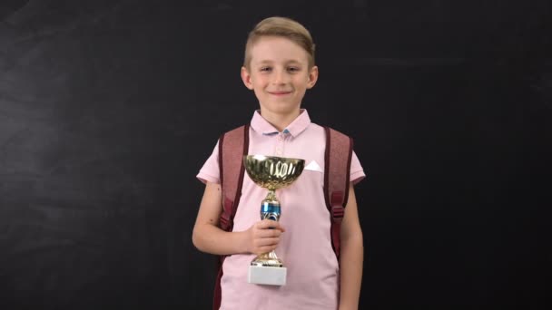 Усміхнений початковий школяр, що володіє кубковою нагородою, переможець чемпіонату, успіх — стокове відео