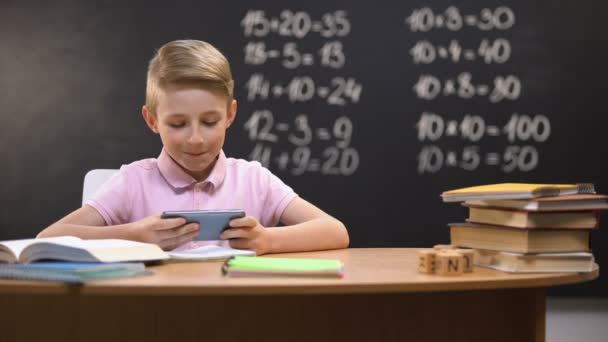 Τεμπέλης μαθητής παίζει βιντεοπαιχνίδια στο τηλέφωνο αντί για την προετοιμασία του έργου, gadget — Αρχείο Βίντεο