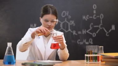 Kimya öğrencisi laboratuvarda sıvıları karıştırma ve sonuçları yazma, deney