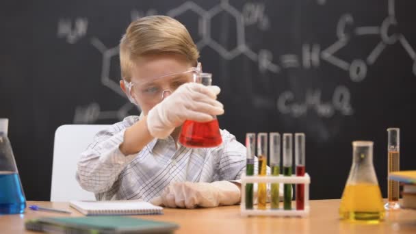 Colegial mirando sedimentos en frasco y escribiendo resultados, lección de química — Vídeos de Stock