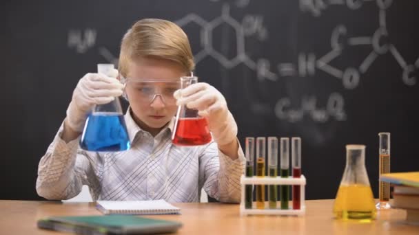 Pequeno nerd comparando líquidos em frascos e escrevendo resultados de reação, inovação — Vídeo de Stock