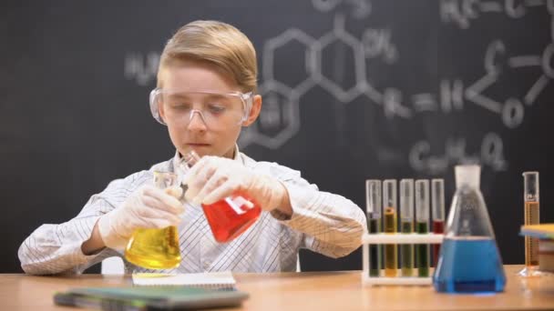 Pojke i skyddsglasögon blandning kemiska vätskor i kolvar, nyfiken geni — Stockvideo