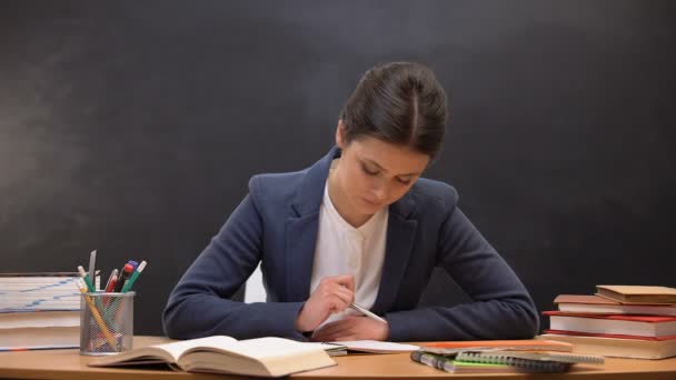 Jovem professora verificando tarefas escolares, ocupação, papelada — Vídeo de Stock