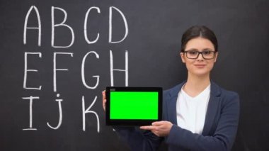 Gülen öğretmen prekeyed tablet tutan, kara tahta üzerinde alfabe, yenilikler