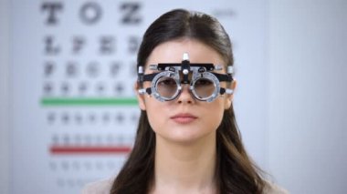 Kadın phoropter bir göz kapanış ve gülümseyerek, doğru lens diyoptri seçimi