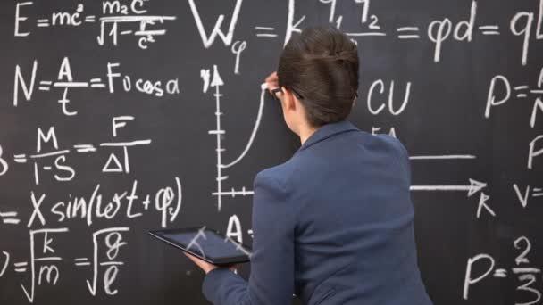 Female teacher drawing graph on chalkboard and holding tablet, innovations — Stock Video