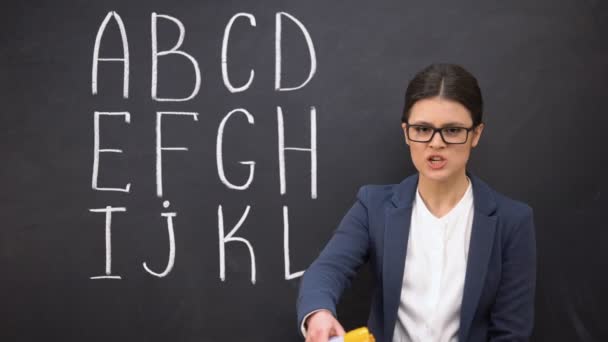 Nervous teacher shouting in megaphone claiming attention, alphabet on blackboard — Stock Video
