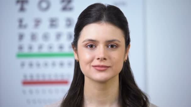 Señora atractiva sonriendo a la cámara durante la visita al optometrista, chequeo de la vista — Vídeos de Stock