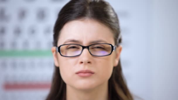 Paciente femenina con gafas inapropiadas apretando los ojos, sufriendo visión borrosa — Vídeo de stock