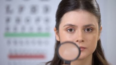 Büyüteçle bakan güzel kadın, fundus muayenesi, check-up