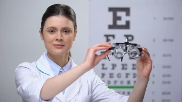Amigável senhora optician empurrando quadro julgamento óptico para a câmera, teste de visão — Vídeo de Stock