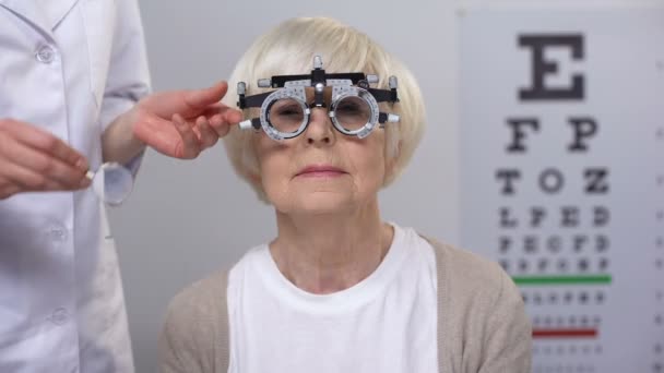 Ottico scegliere lente corretta per la donna anziana in cornice di prova ottica, check-up — Video Stock