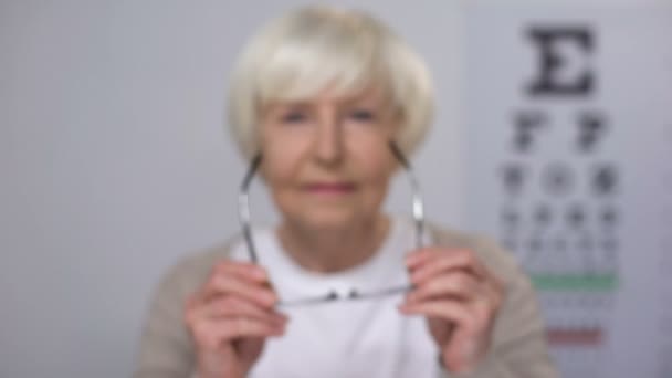 Rentnerin setzt Brille auf und fokussiert Sehen, Termin beim Optiker — Stockvideo