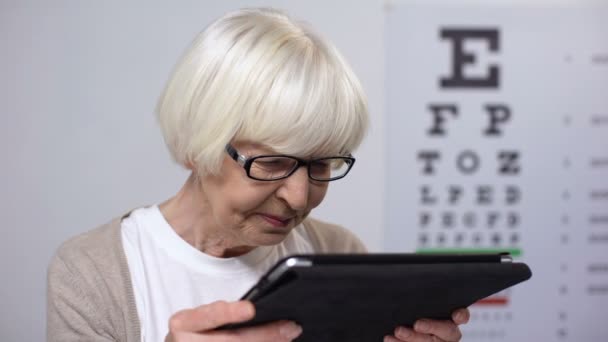 Skrynkliga äldre kvinna hålla tab och försöker läsa, missnöjd med dålig syn — Stockvideo