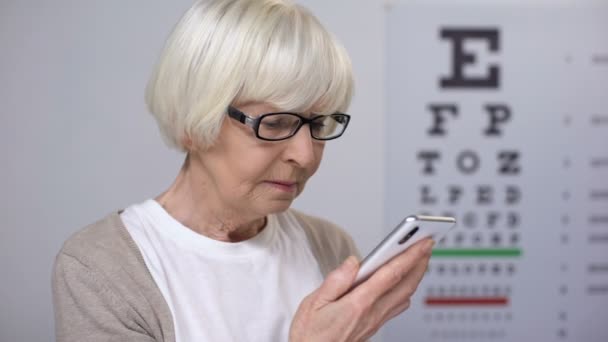 Mujer mayor tratando de leer en el teléfono inteligente, fuente pequeña, problemas de visión pobres — Vídeos de Stock