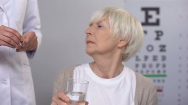 Doktor yaşlı kadın hasta hapı veren, yüksek göz basıncını azaltarak, vitaminler