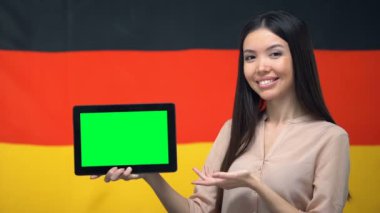 Yeşil ekranlı tablet tutan kız, arka planda Almanya bayrağı, göç