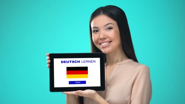 Женщина держит планшет с немецким приложением, готова начать курс — стоковое видео