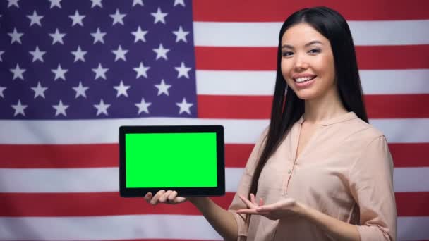 Девушка держит планшет с зеленым экраном, флаг США на заднем плане, миграция — стоковое видео