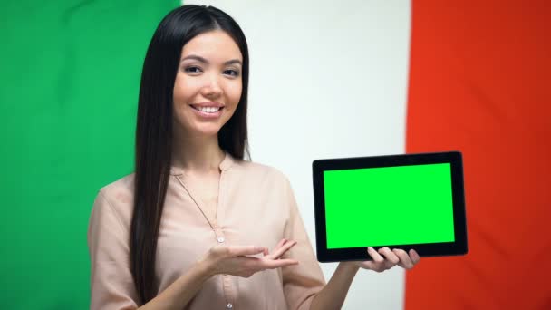 Niña sosteniendo la tableta con pantalla verde, bandera italiana en el fondo, migración — Vídeo de stock