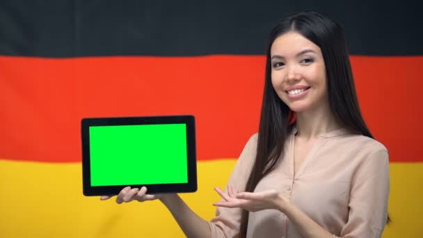 Niña sosteniendo la tableta con pantalla verde, bandera de Alemania en el fondo, migración — Vídeos de Stock