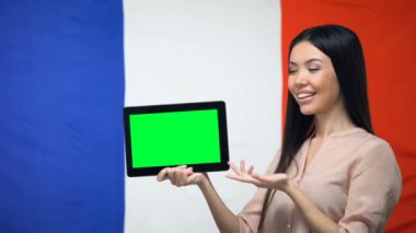 Kız yeşil ekranlı tablet tutan, arka planda Fransa bayrağı, göç