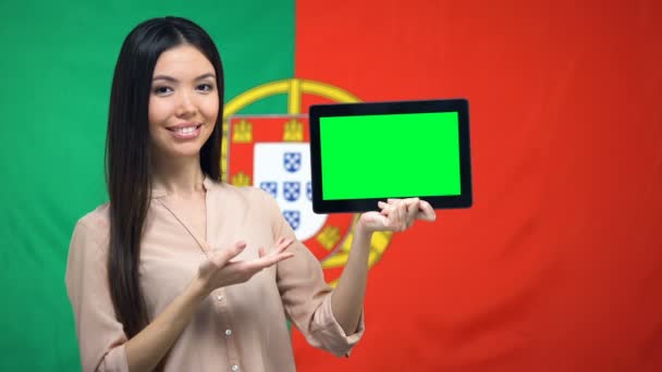 Niña sosteniendo la tableta con pantalla verde, bandera portuguesa en el fondo, migración — Vídeo de stock