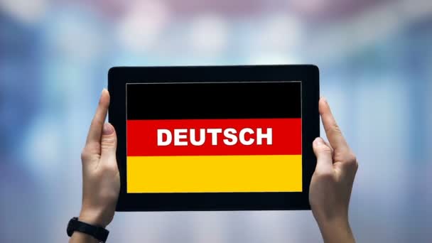 Жіночі руки тримають планшет з німецьким словом проти національного прапора, онлайн додаток — стокове відео