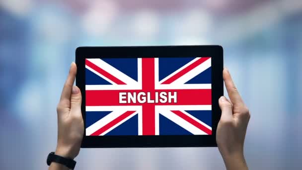 Kobiece ręce trzymając tablet z angielskiego słowa przeciwko brytyjskiej flagi, aplikacja online — Wideo stockowe