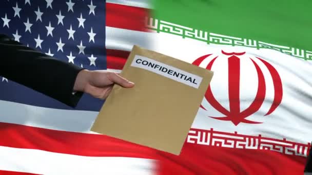 USA und iranische Beamte tauschen vertraulichen Umschlag aus, Flaggen im Hintergrund — Stockvideo