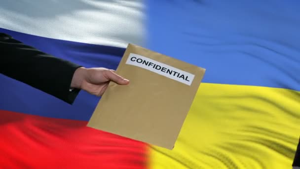 Russia and Ukraine officials exchanging confidential envelope, flags background — Stock Video