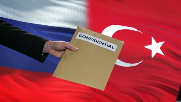 Russia and Turkey officials exchanging confidential envelope, flags background — Stock Video